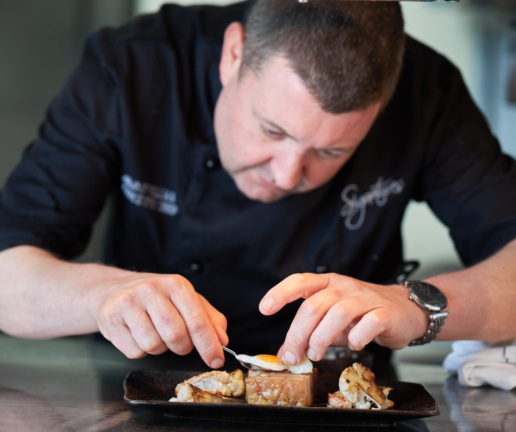 Owner of Signatures restaurant plating up food