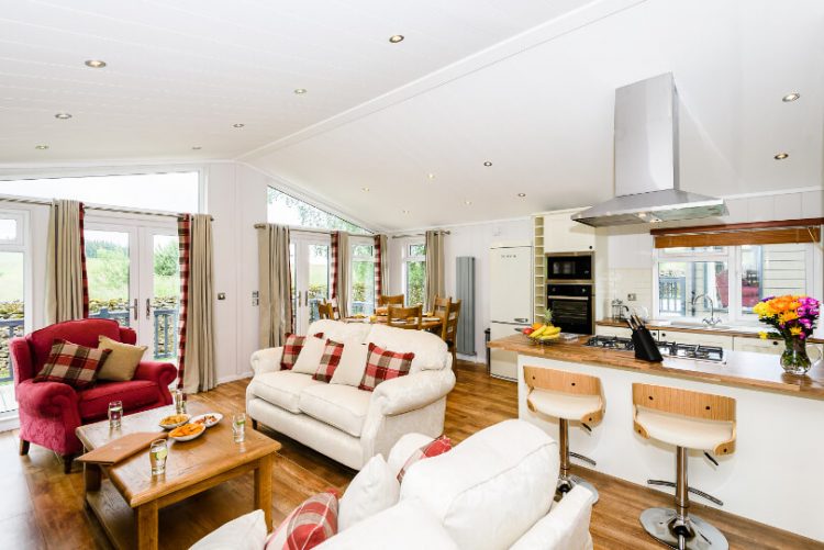 wide view of living room including sofas, armchair, kitchen island and breakfast stools 