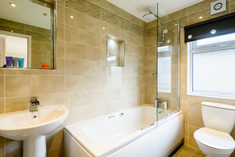 tiled bathroom with integrated shower/bath toilet and basin