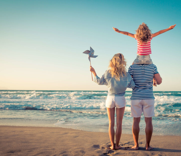 family of three on beach with dad on girls shoulders