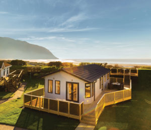 larger ownership lodge at aberconwy resort at sunset, with the beach, sea and mountain in the backdrop