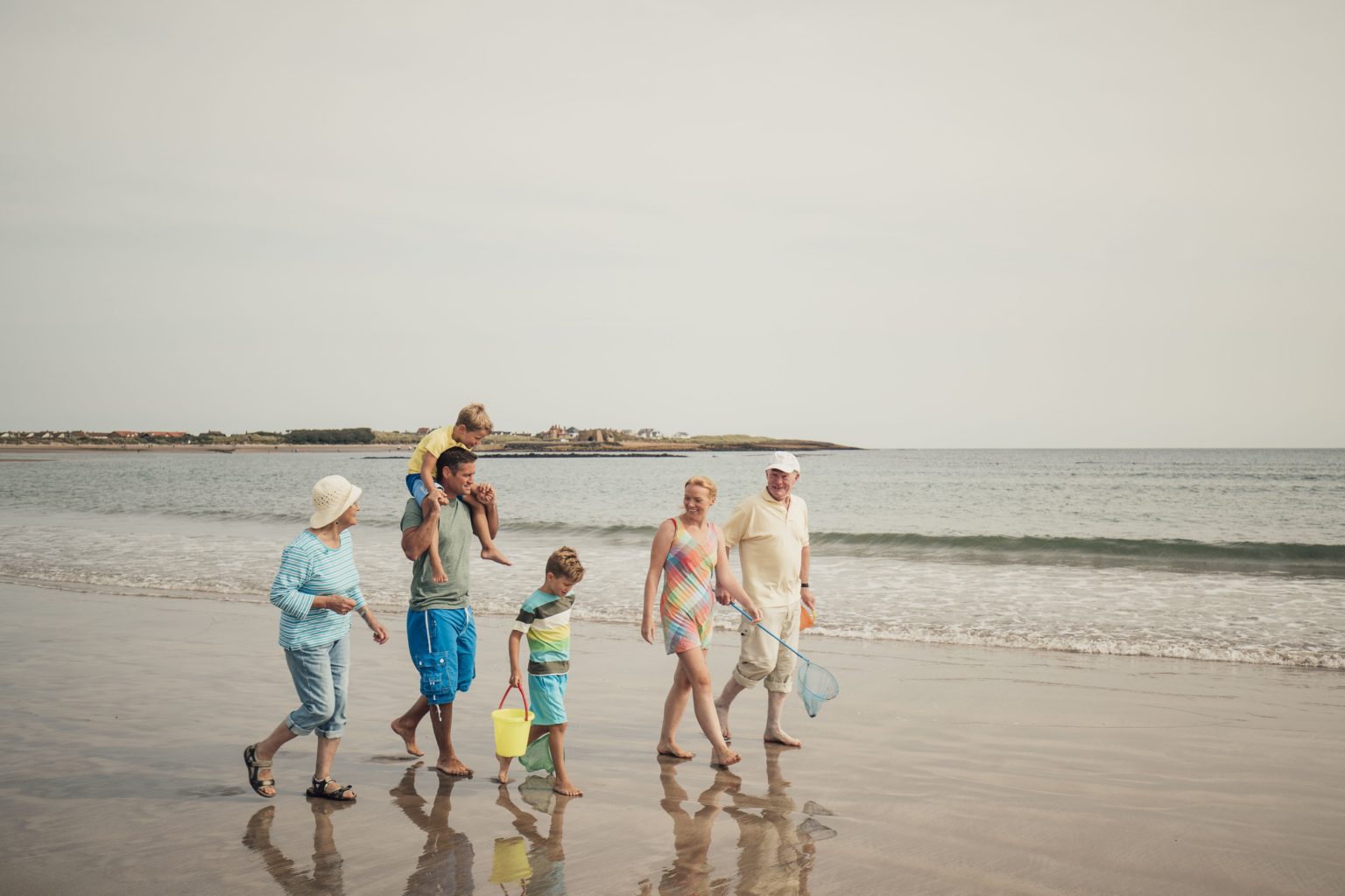 A large family take a walk on the beach together.