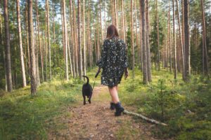 Woman and her dog walking through a forest