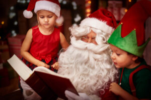 Two children stood with Santa reading through their Christmas list