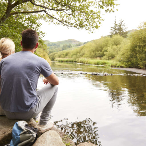 couple sat on rocks near waters edge in the Lake District