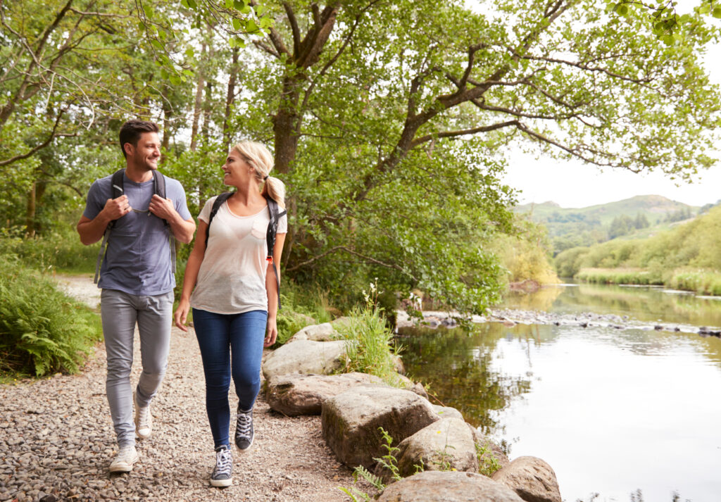 couple walking and talking in woodland next to the lake