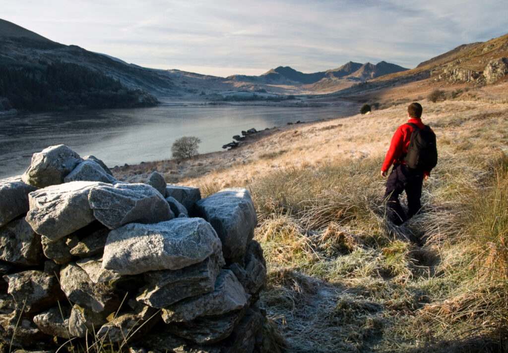 man standing on a hill overlooking a great lake in the lake district