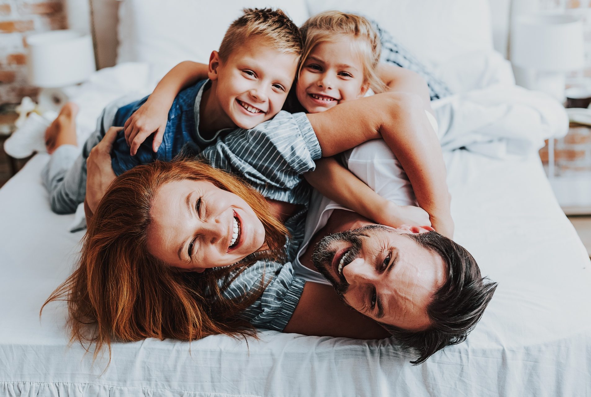 family hugging on caravan bed, white linen