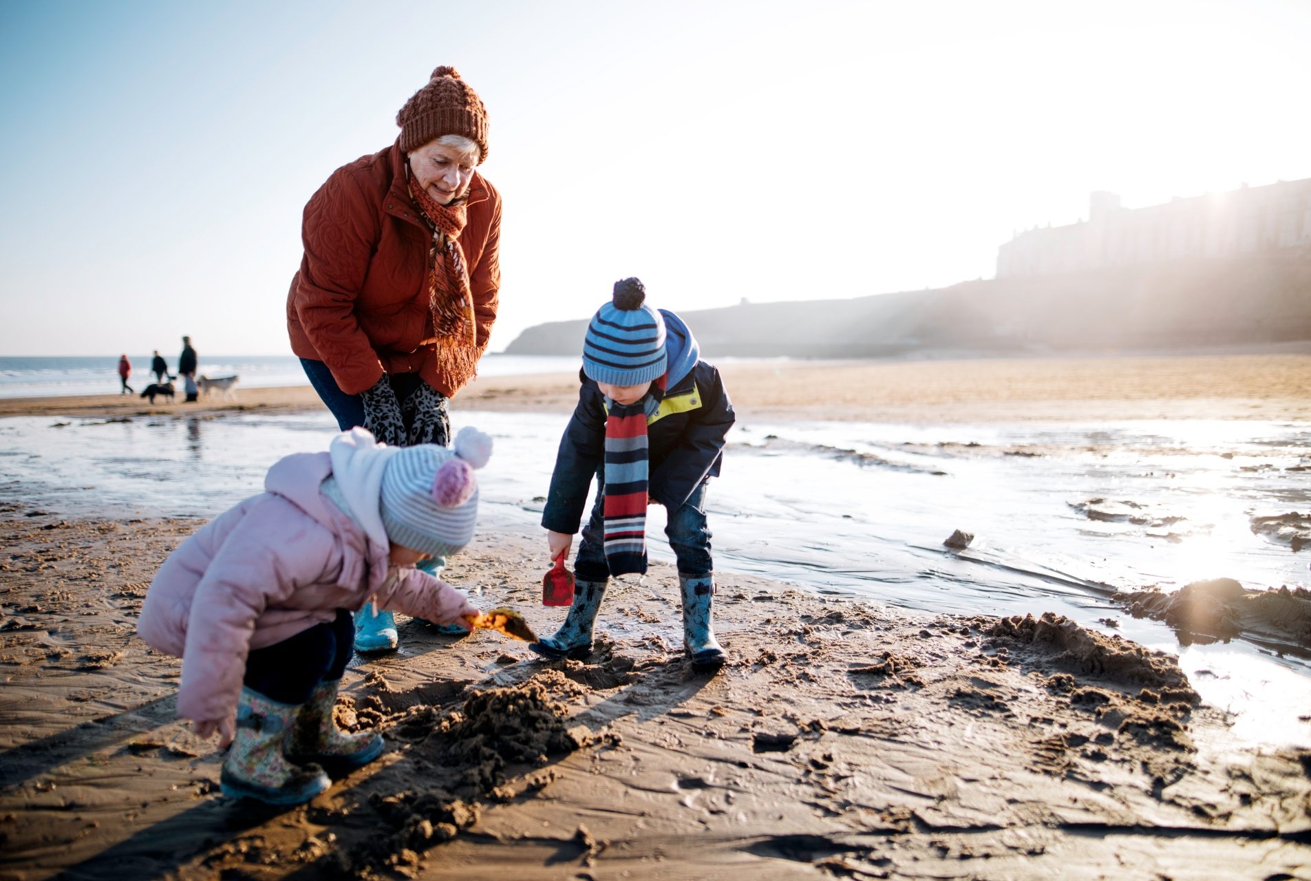 family in hats and scarves digging on the beach
