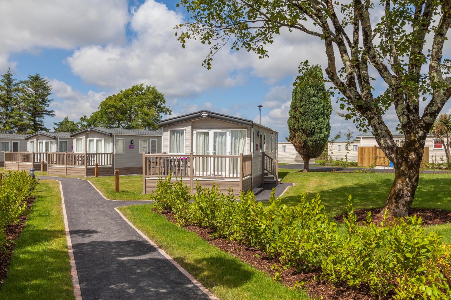 caravans surrounded by trees, grass and blue skies
