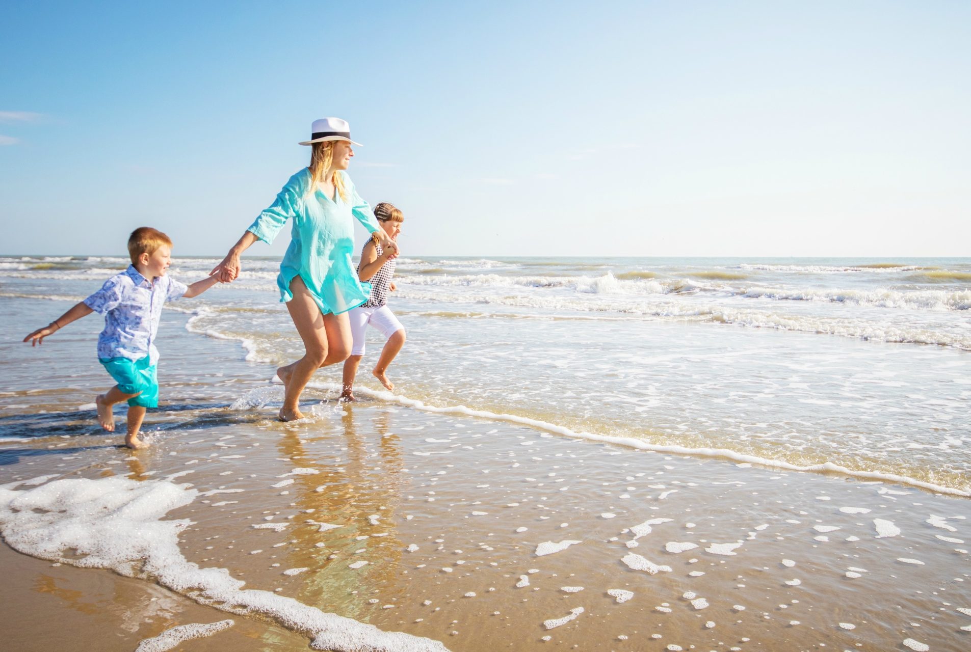 mum and 2 children paddle in the shore