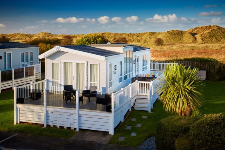 Large caravan with decking with a sand dune backdrop