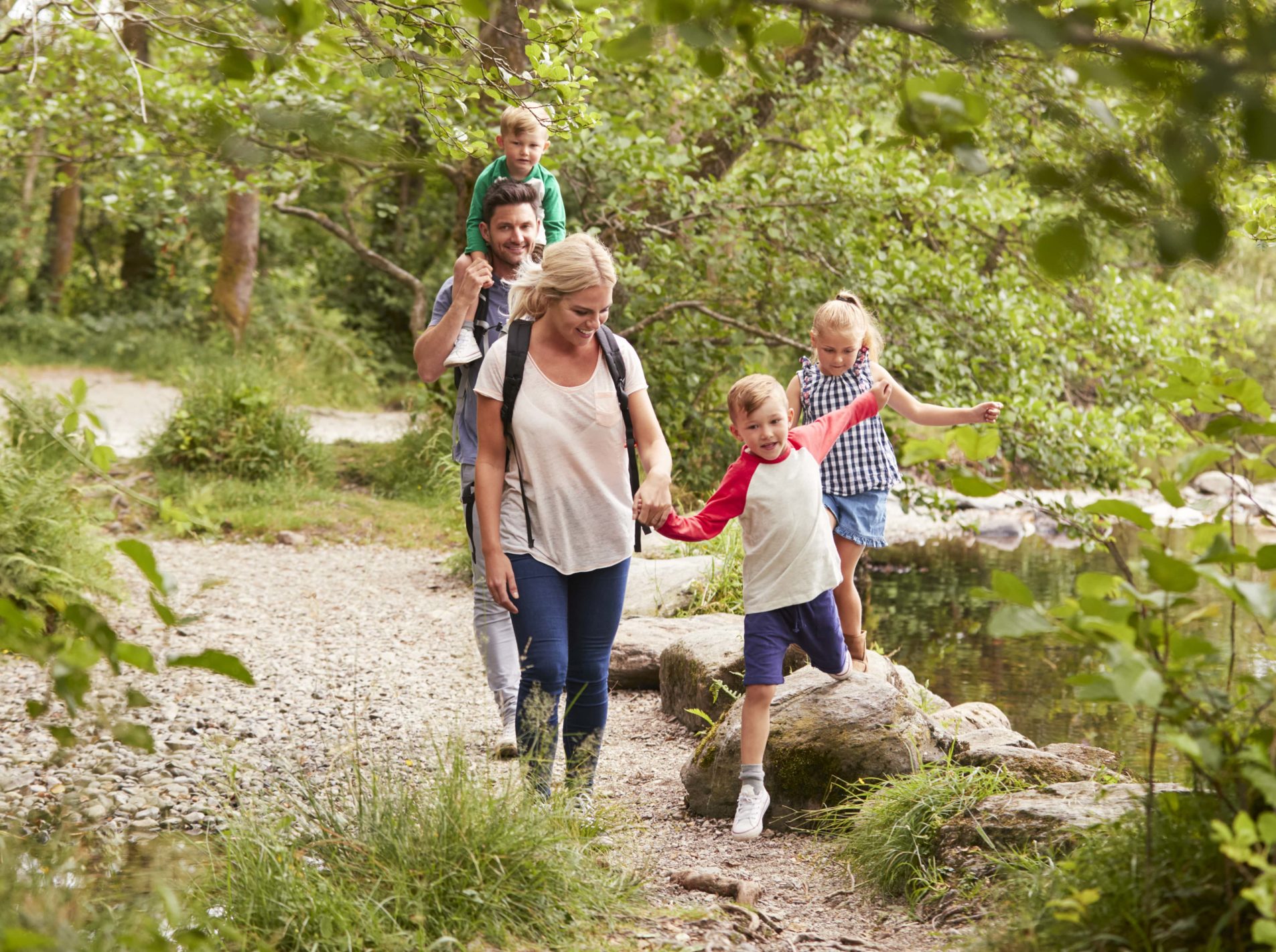 Family of four walking through the woods and dodging the big stones on the floor
