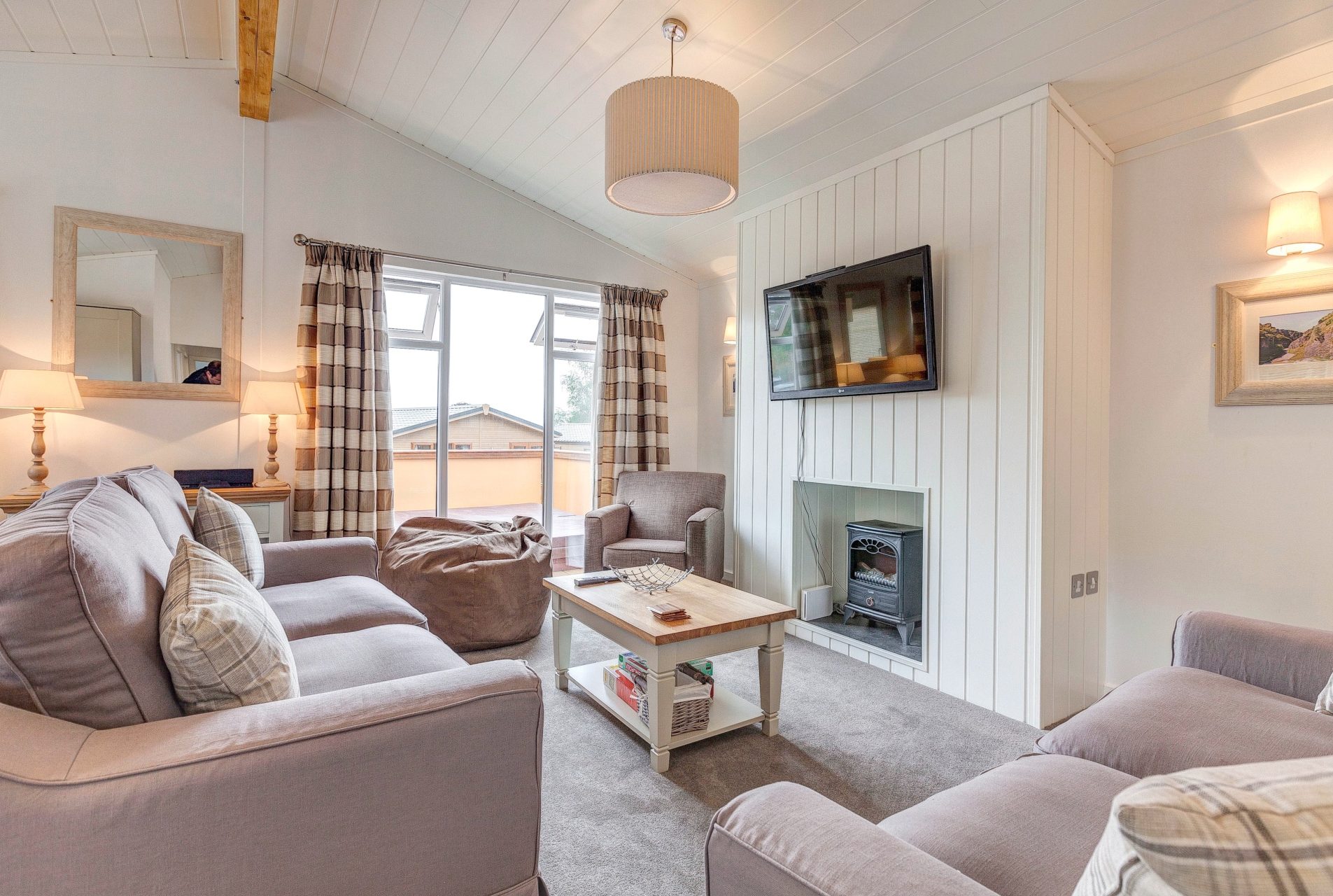 Country-feel decor in a lodge lounge. n imitation log burner and large TV sit on a feature wooden-clad wall