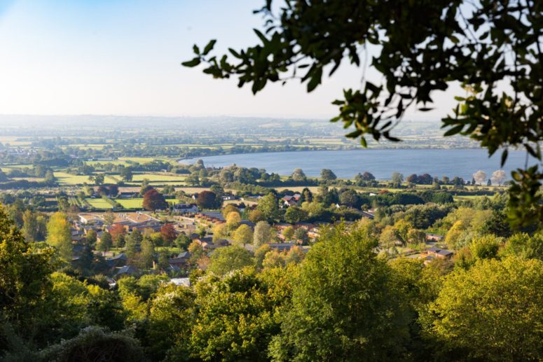 Cheddar Reservoir can be seen from the hills above. beautiful green trees and fields fill the shot