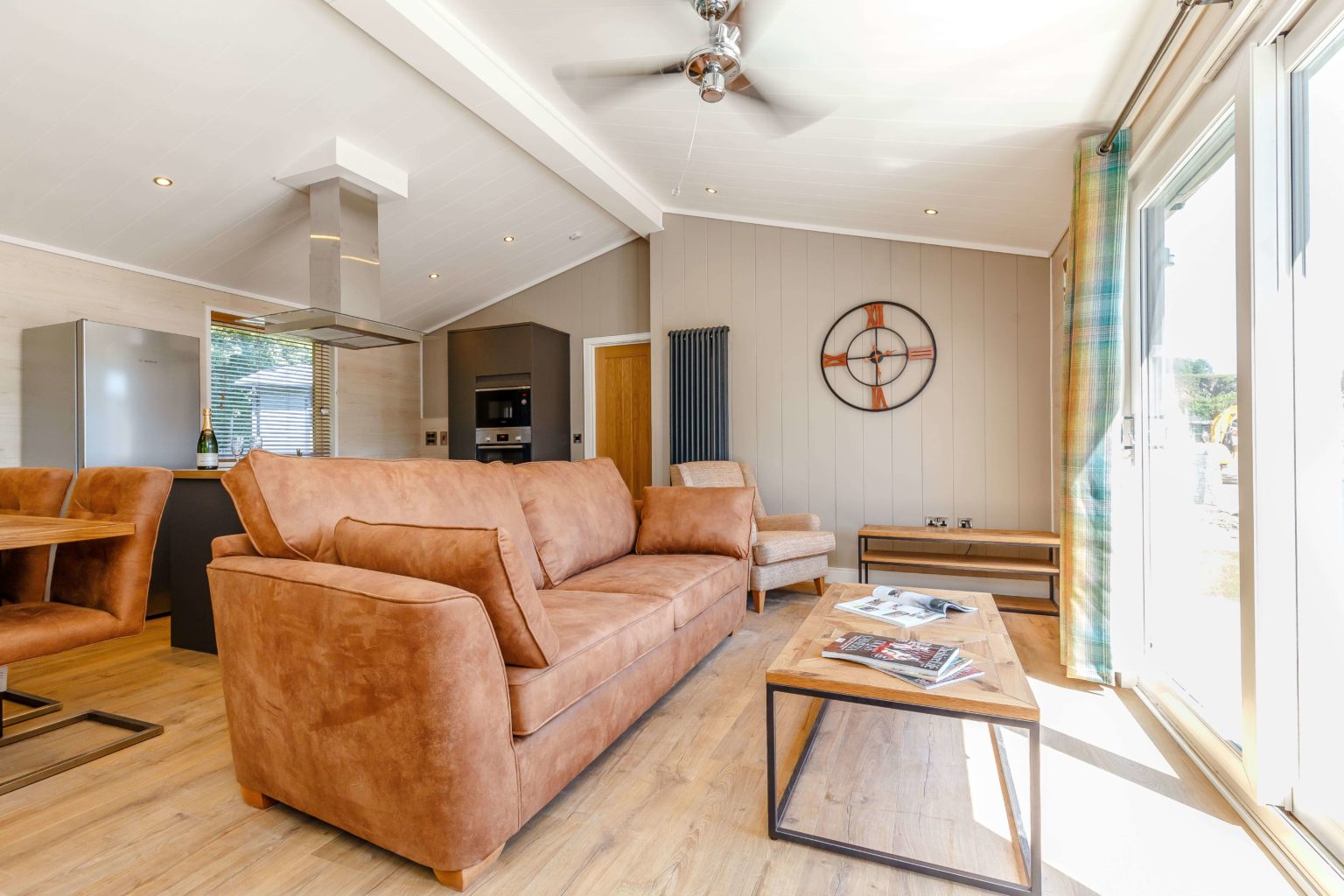 An interior shot of one of the lodges at Rivendale with light brown sofas and an open plan living and kitchen area