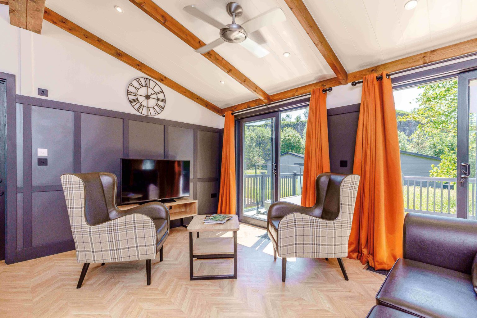 An interior shot of one of the lodges which shows two armchairs by the television