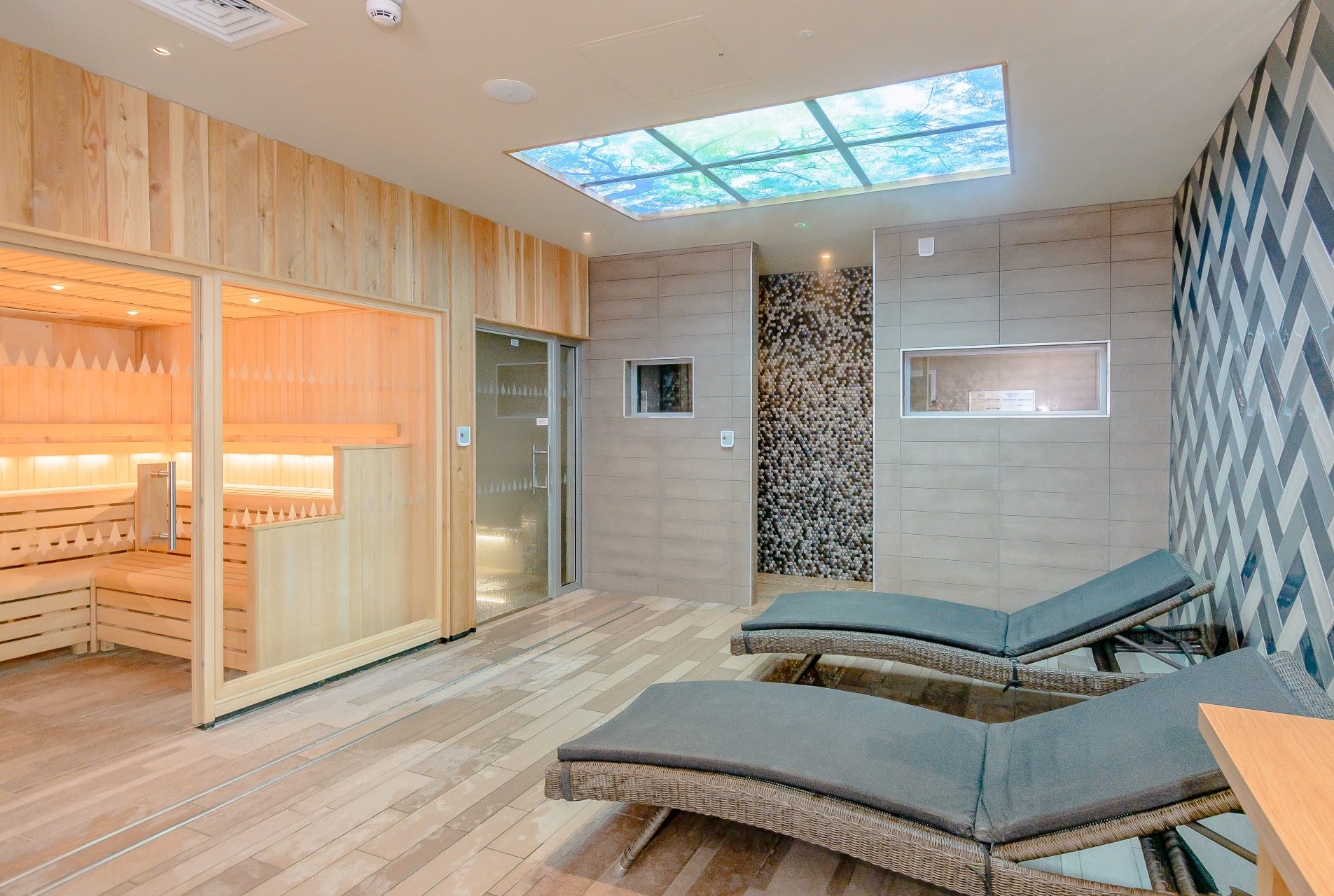 Sleek relaxation room with sauna steam room shower and beds. Funky zigzag tiles on the wall