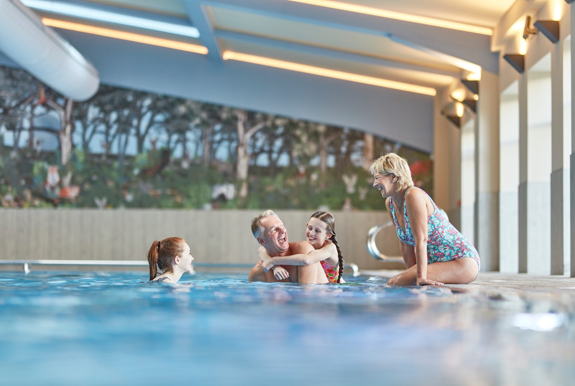 granchildren and grandparents enjoy the pool, Grandma sits on the side, grandad gives a piggyback