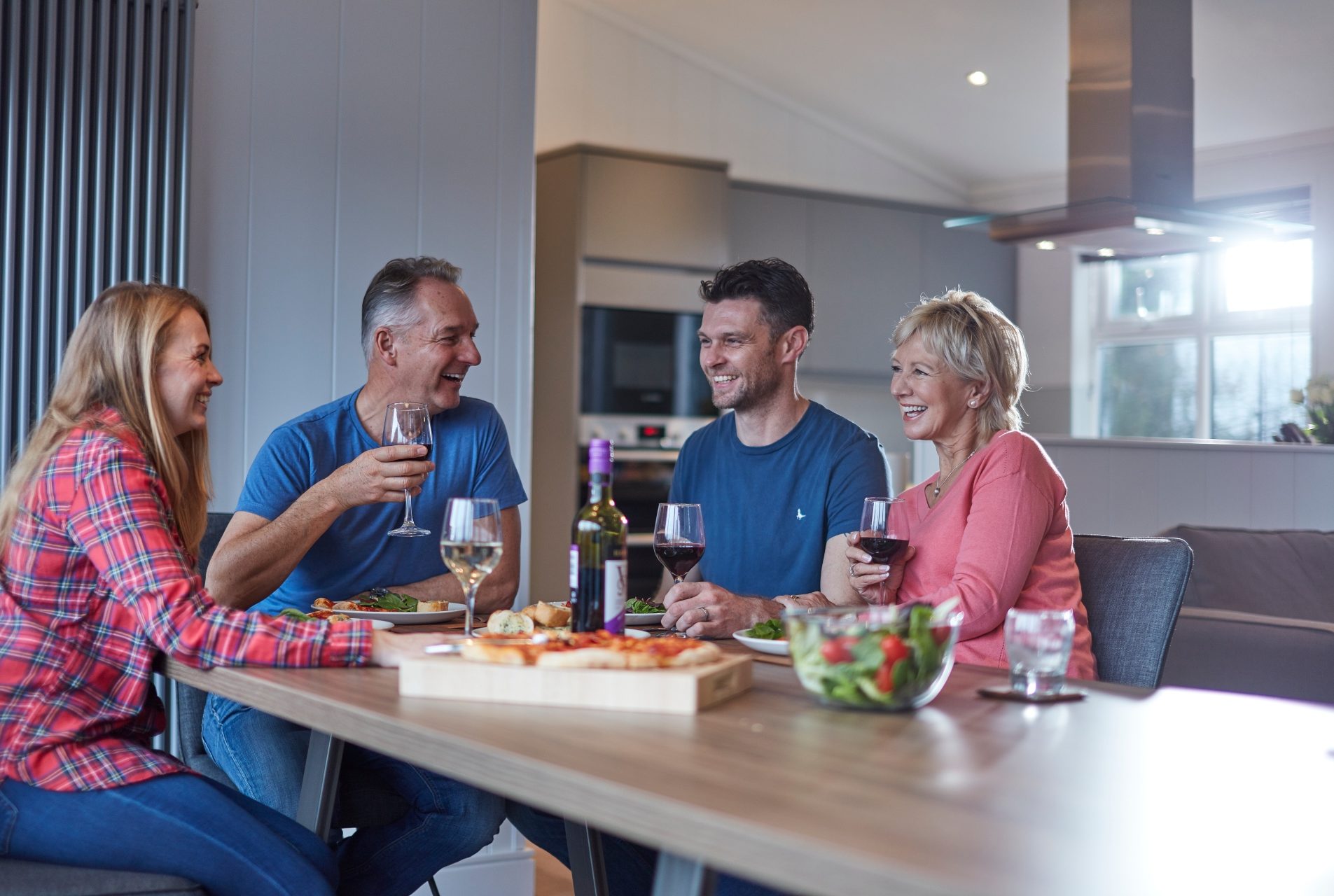 2 adult couples enjoy wine and pizza in a lodge dining area