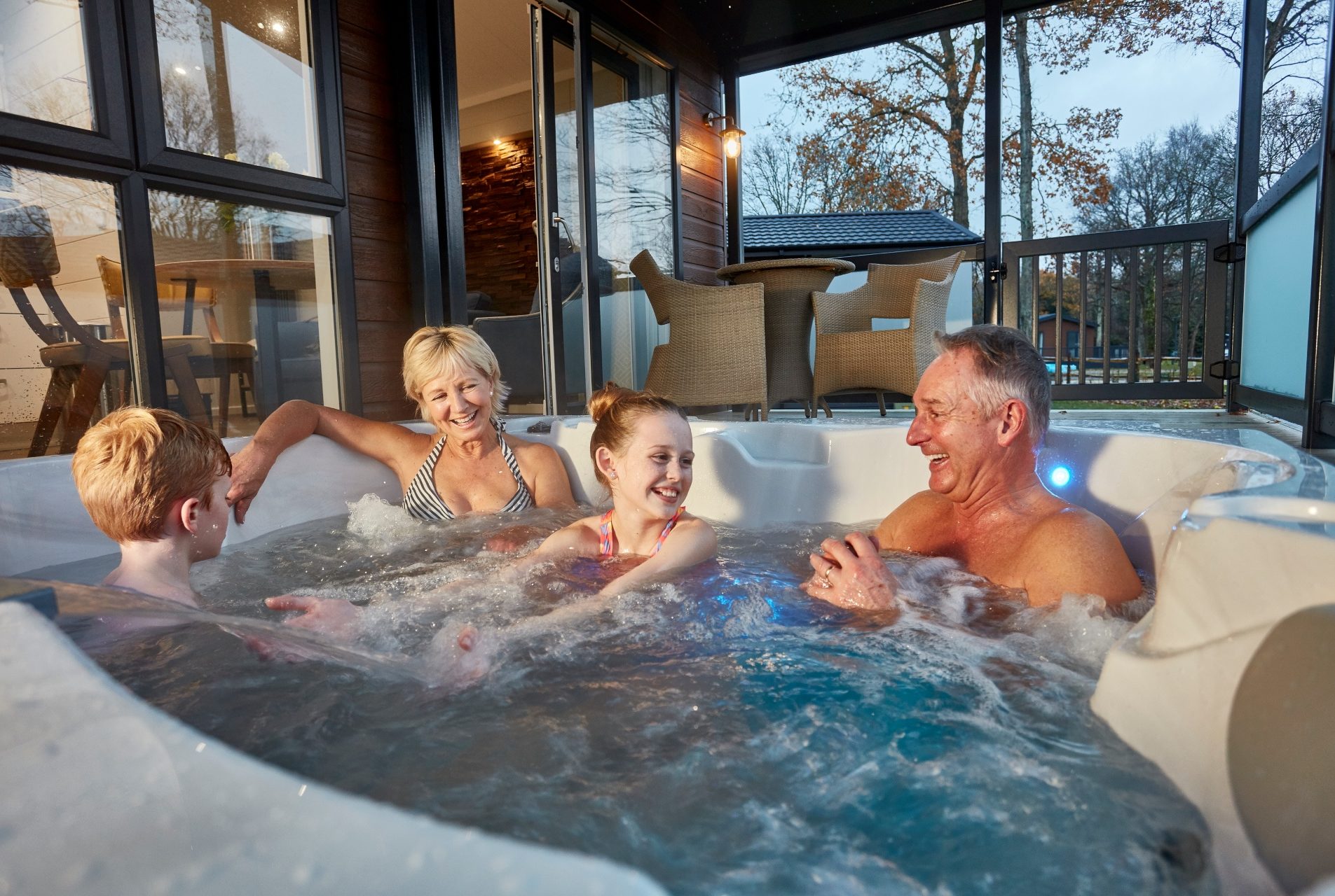 grandchildren and grandparents enjoy the hot tu on a lodge decking