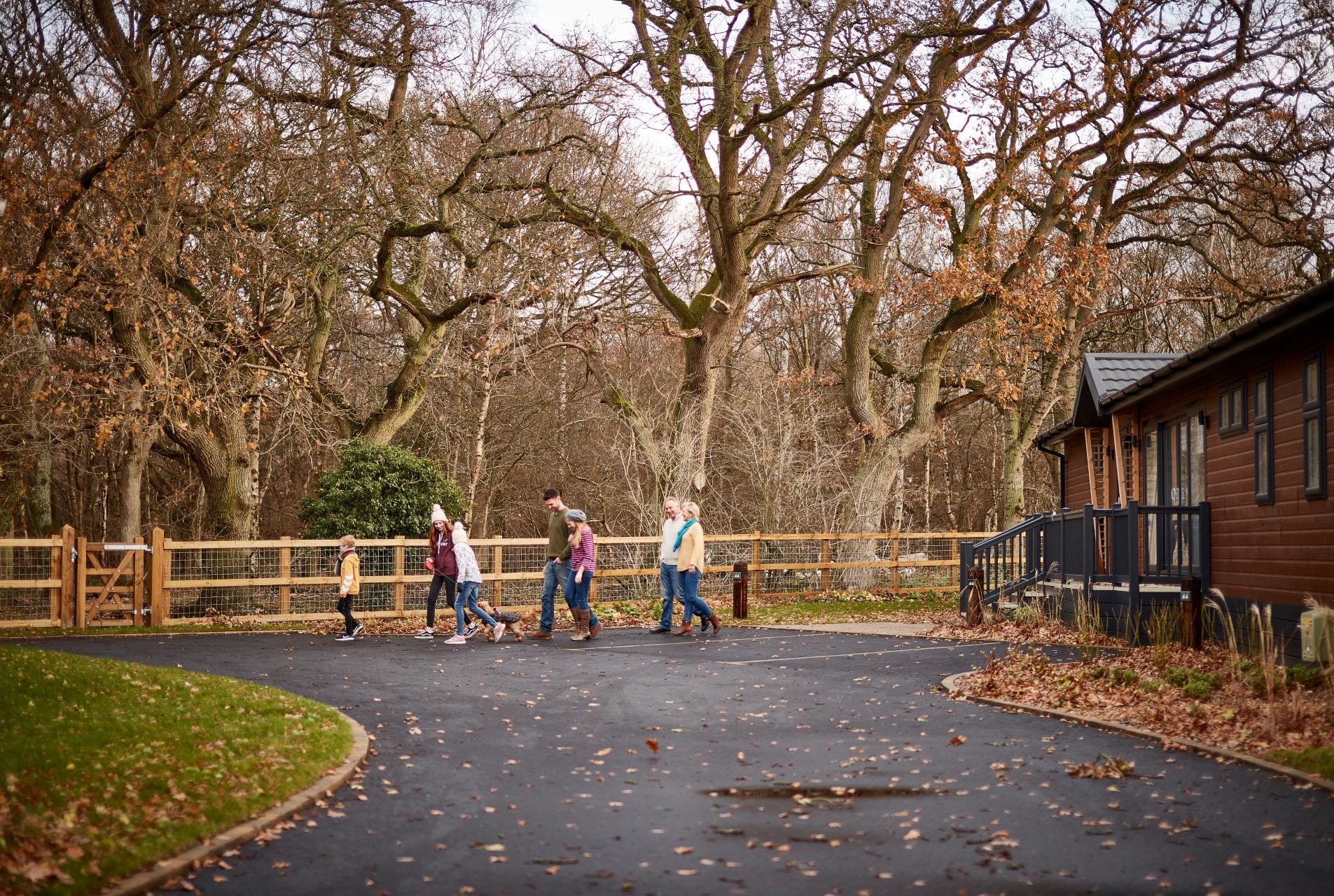 Family dressed for autumn walk a dog near a lodge and lots of bare trees