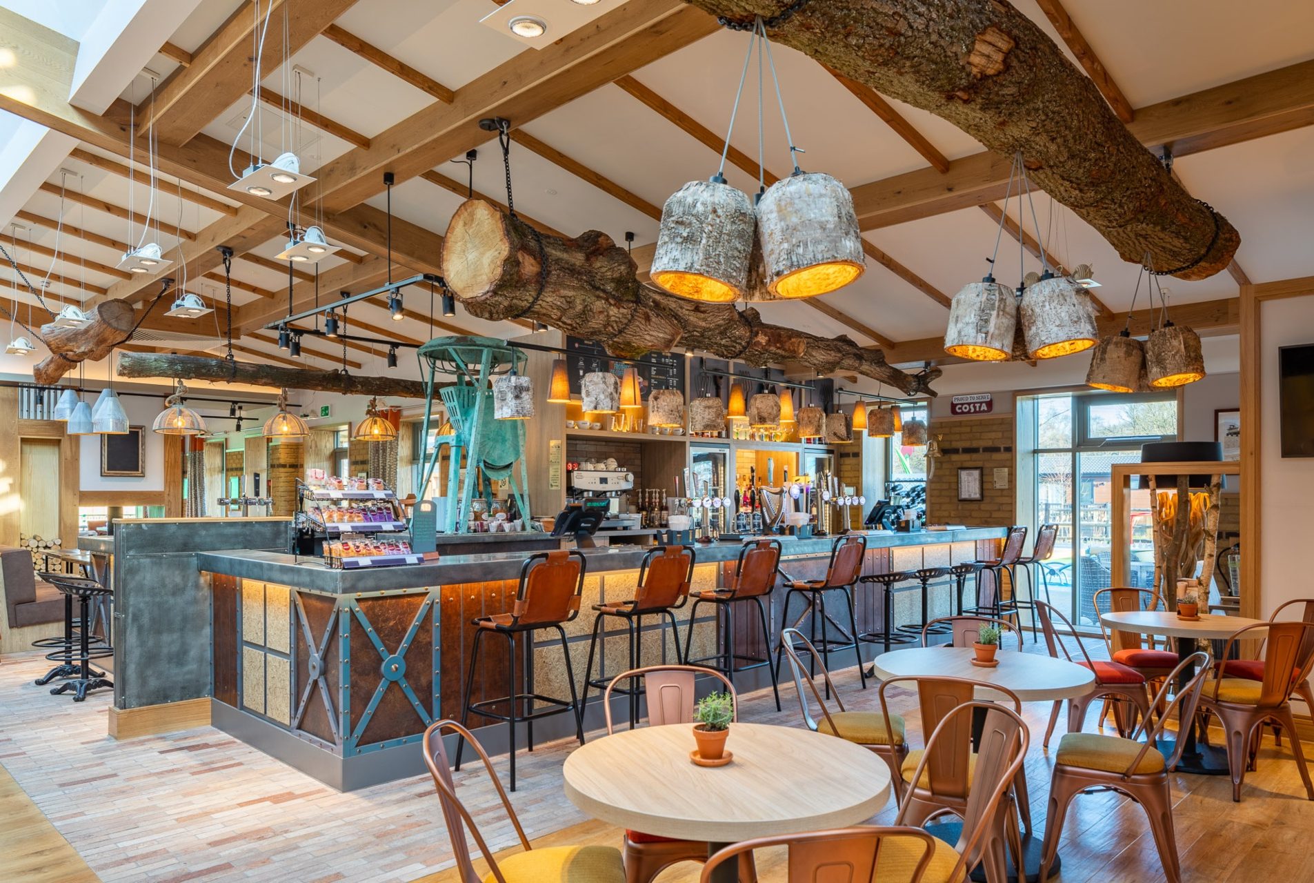 Ultra-modern bar and tables with feature tree trunks hanging from a beamed ceiling