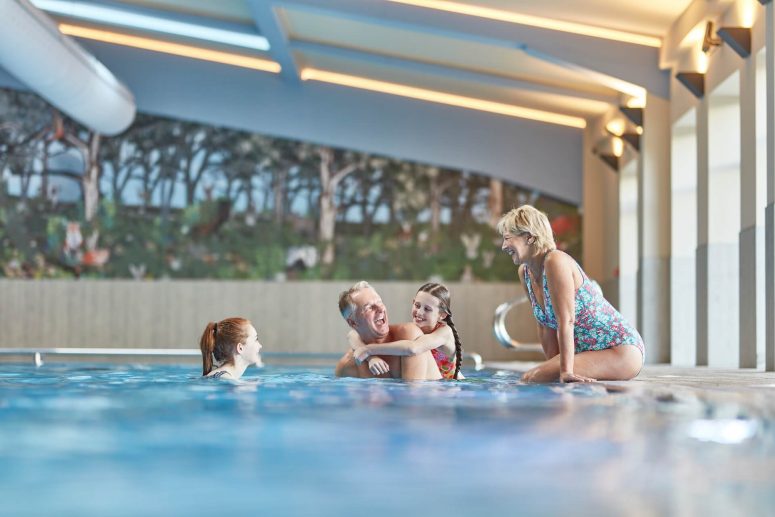 granchildren and grandparents enjoy the pool, Grandma sits on the side, grandad gives a piggyback