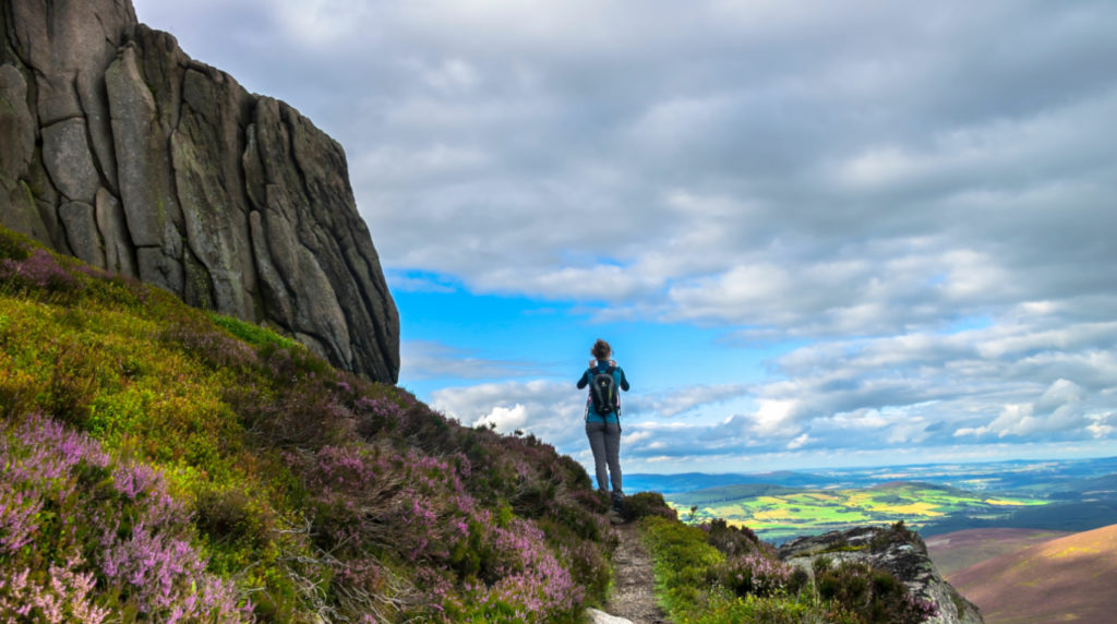 woman walking up a mountain, showing landscapes