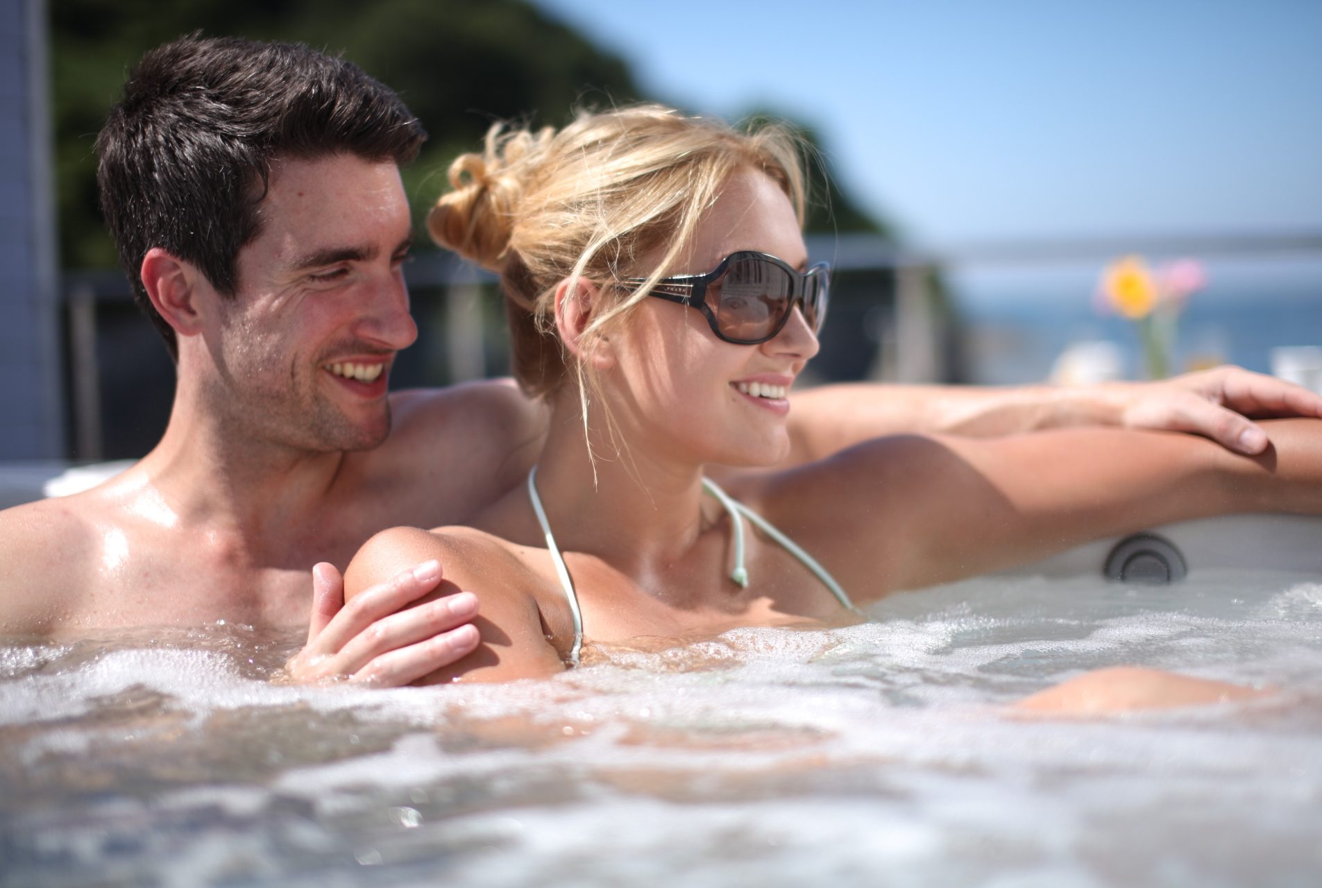 happy couple n a hot tub with sea views behind