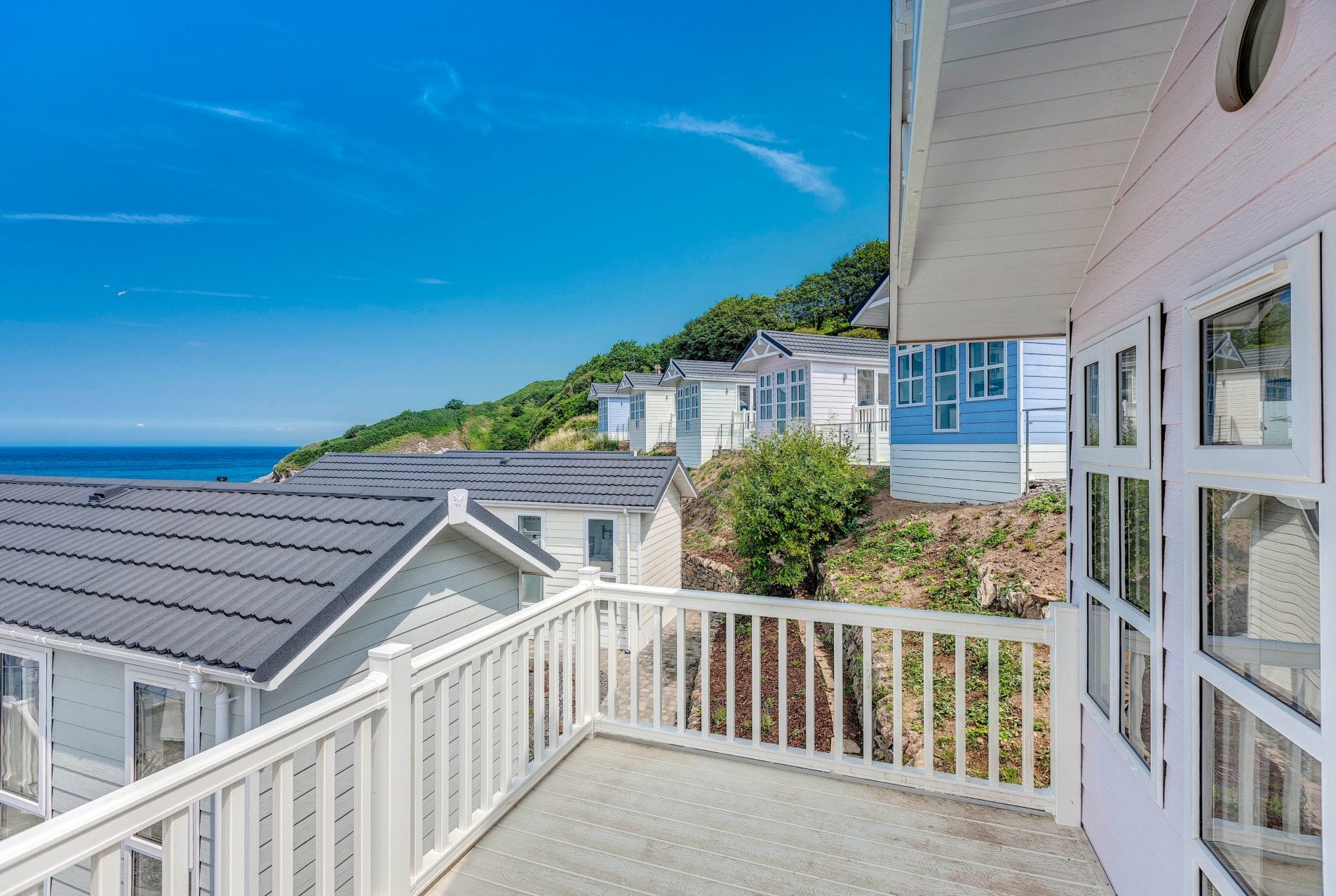 pastel coloured beach huts in a row with blue skies
